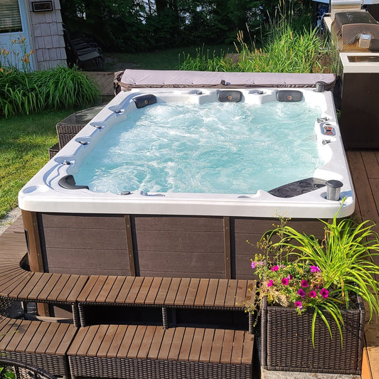 Outdoor-Whirlpool mit Rattan Treppe und modularer Randmöblierung im Garten.